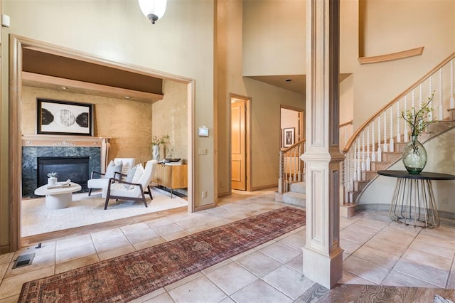 tiled foyer entrance featuring a towering ceiling and a fireplace