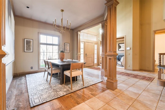 tiled dining area featuring crown molding, an inviting chandelier, decorative columns, and a high ceiling