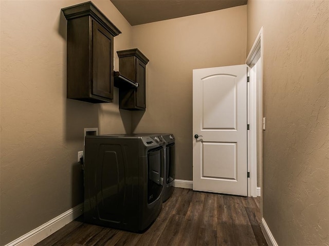 laundry area featuring cabinets, washing machine and dryer, and dark hardwood / wood-style floors