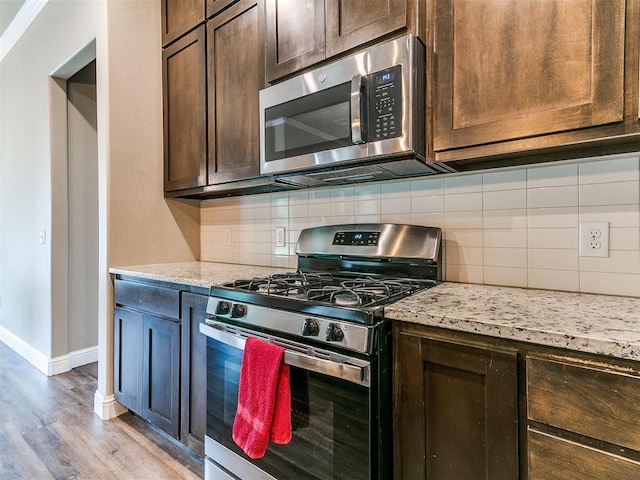 9015 Tall Oaks Dr, Guthrie, OK 73044 - kitchen featuring appliances with stainless steel finishes, light wood-style floors, dark brown cabinets, baseboards, and tasteful backsplash