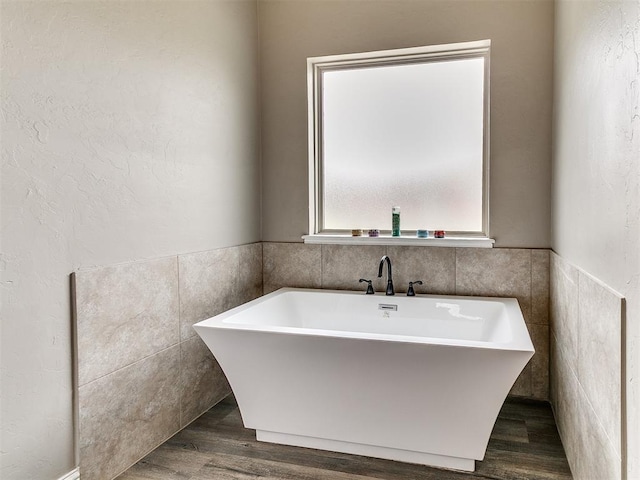 9015 Tall Oaks Dr, Guthrie, OK 73044 - full bathroom with a soaking tub, wood finished floors, tile walls, and a wainscoted wall