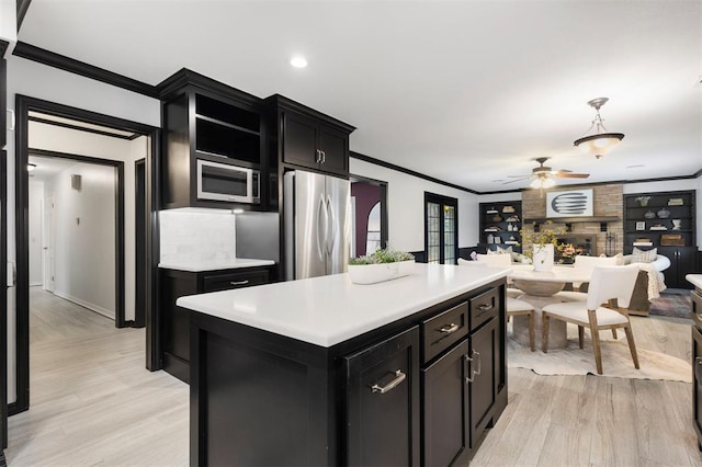 kitchen with crown molding, decorative light fixtures, a center island, and appliances with stainless steel finishes