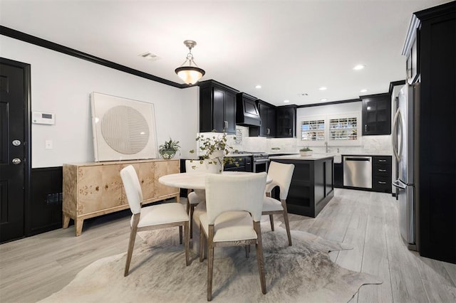 dining area with ornamental molding, sink, and light hardwood / wood-style floors