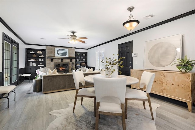 dining area with ornamental molding, hardwood / wood-style floors, and a fireplace