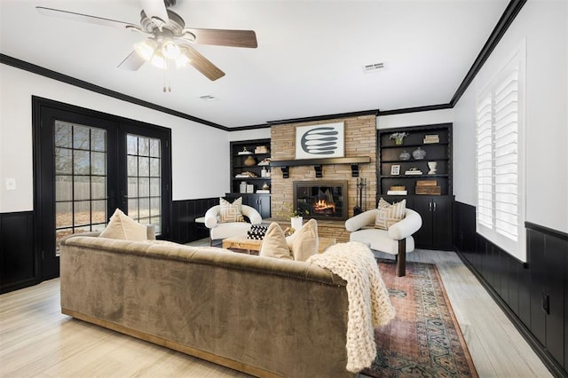 living room with light hardwood / wood-style flooring, a fireplace, ornamental molding, and french doors