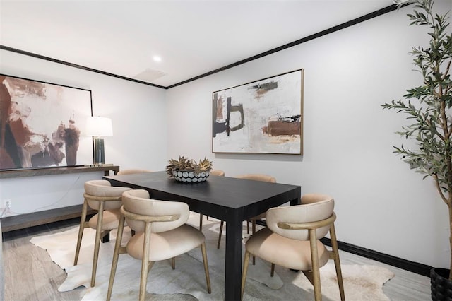 dining room with crown molding and light hardwood / wood-style floors