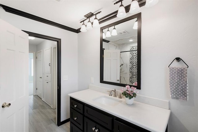 bathroom featuring vanity, hardwood / wood-style floors, crown molding, and walk in shower