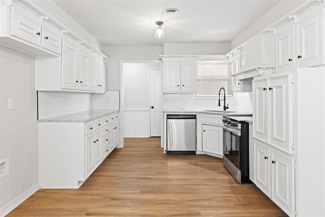 kitchen with sink, appliances with stainless steel finishes, light hardwood / wood-style floors, decorative backsplash, and white cabinets