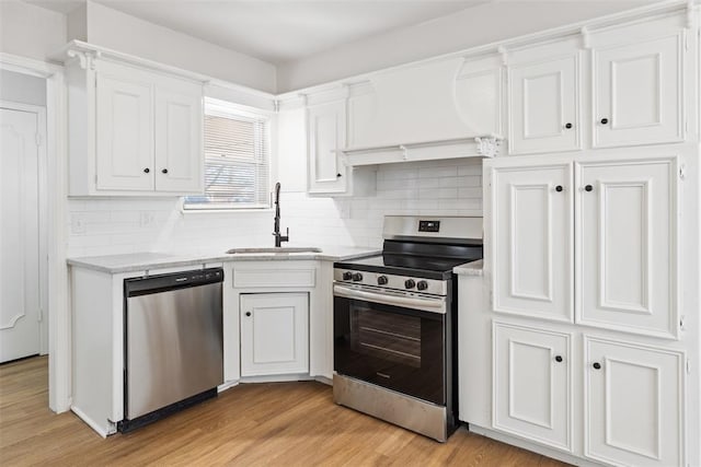 kitchen with stainless steel appliances, sink, white cabinets, and light hardwood / wood-style floors