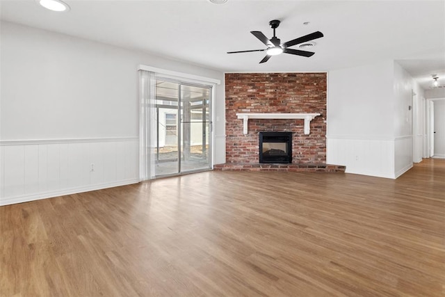 unfurnished living room with a brick fireplace, hardwood / wood-style floors, and ceiling fan