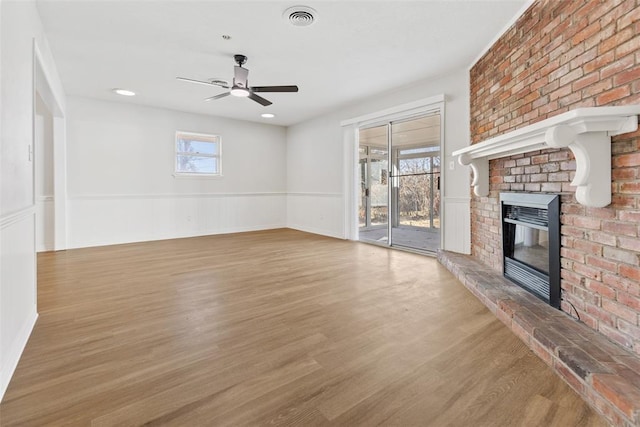 unfurnished living room with ceiling fan, wood-type flooring, and a brick fireplace