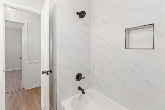 bathroom featuring wood-type flooring and tiled shower / bath