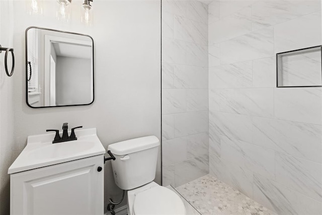 bathroom featuring vanity, toilet, and a tile shower