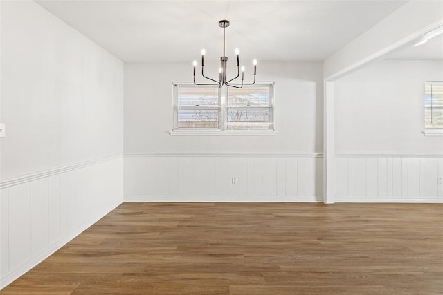 unfurnished dining area featuring a notable chandelier and wood-type flooring