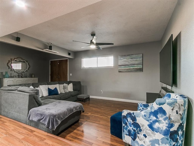 living room featuring wood-type flooring, a textured ceiling, and ceiling fan