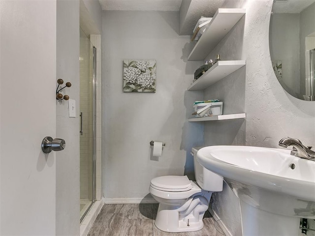 bathroom with a shower with door, sink, and toilet