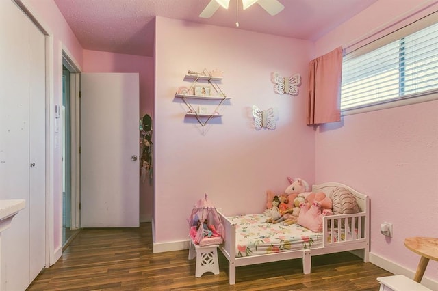 bedroom featuring dark wood-type flooring, a textured ceiling, and ceiling fan