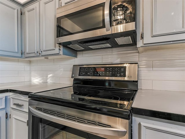 kitchen featuring backsplash, gray cabinets, and appliances with stainless steel finishes