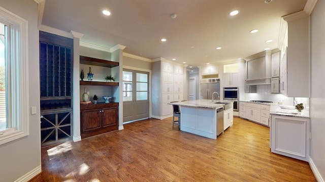 kitchen featuring stainless steel appliances, an island with sink, a breakfast bar, and white cabinetry