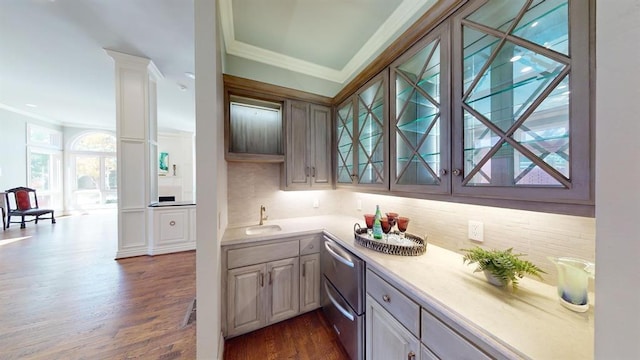 kitchen with sink, ornamental molding, dark hardwood / wood-style flooring, decorative columns, and decorative backsplash