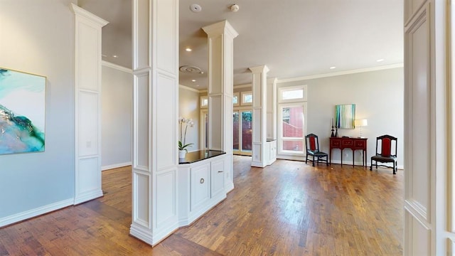 interior space with hardwood / wood-style flooring, ornamental molding, and ornate columns