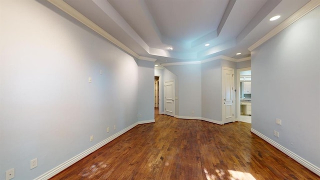 empty room with dark hardwood / wood-style flooring, ornamental molding, and a raised ceiling