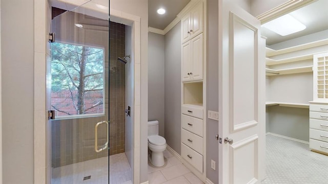 bathroom featuring a shower with door and toilet