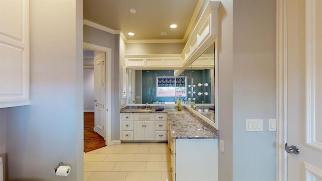 kitchen with white cabinetry, sink, light tile patterned floors, crown molding, and light stone countertops