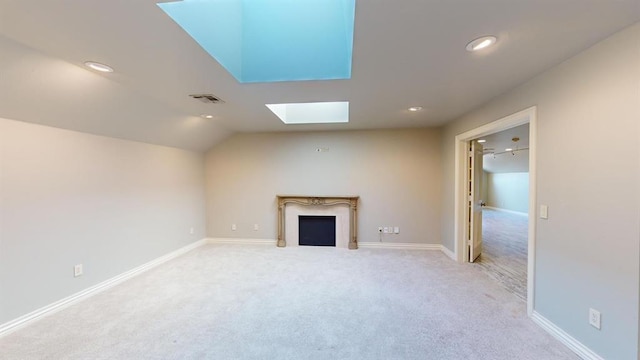 unfurnished living room featuring light colored carpet and vaulted ceiling with skylight