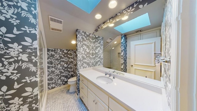 bathroom featuring a skylight, tile patterned flooring, vanity, walk in shower, and toilet