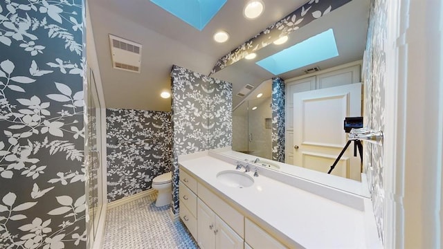 bathroom featuring a skylight, vanity, a shower, tile patterned floors, and toilet