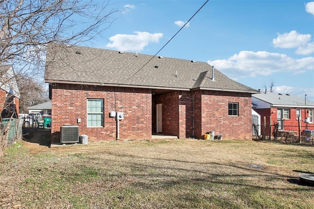 rear view of property with central AC unit and a lawn