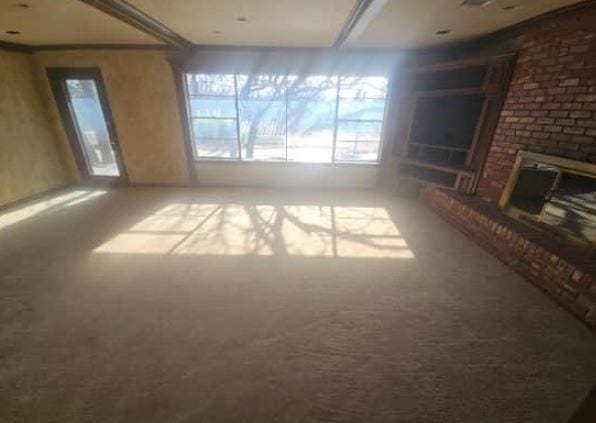 unfurnished living room featuring carpet floors and a brick fireplace