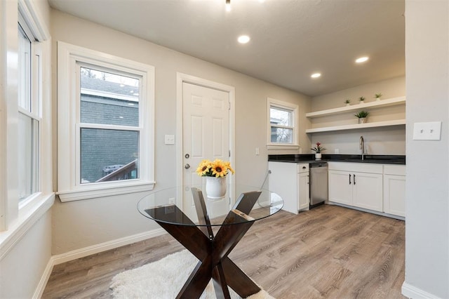 kitchen featuring white cabinetry, sink, stainless steel dishwasher, and light wood-type flooring