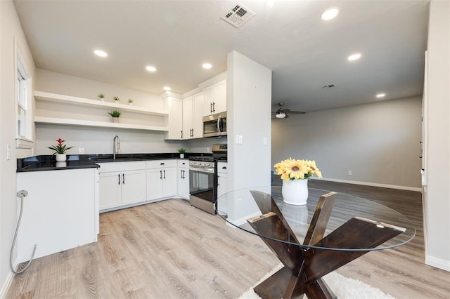 kitchen with sink, light hardwood / wood-style flooring, ceiling fan, stainless steel appliances, and white cabinets