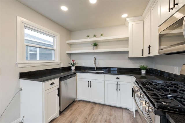 kitchen featuring white cabinetry, appliances with stainless steel finishes, sink, and dark stone countertops