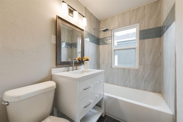 full bathroom featuring vanity, tiled shower / bath, and toilet