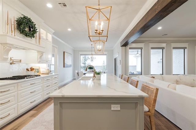 kitchen with a notable chandelier, a sink, visible vents, open floor plan, and stainless steel gas stovetop