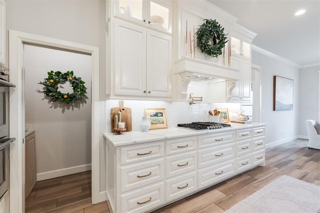 bar featuring baseboards, stainless steel gas stovetop, wood tiled floor, tasteful backsplash, and crown molding