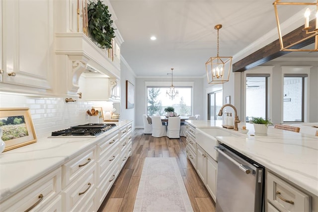 kitchen with wood finish floors, stainless steel appliances, backsplash, a sink, and a chandelier