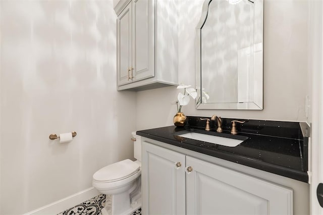 half bathroom featuring tile patterned floors, vanity, toilet, and baseboards