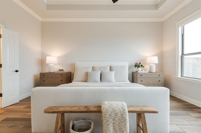 bedroom with ornamental molding, light wood-style flooring, and baseboards