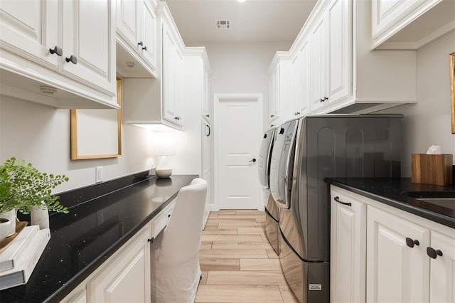 clothes washing area featuring light wood finished floors, visible vents, cabinet space, and washing machine and clothes dryer