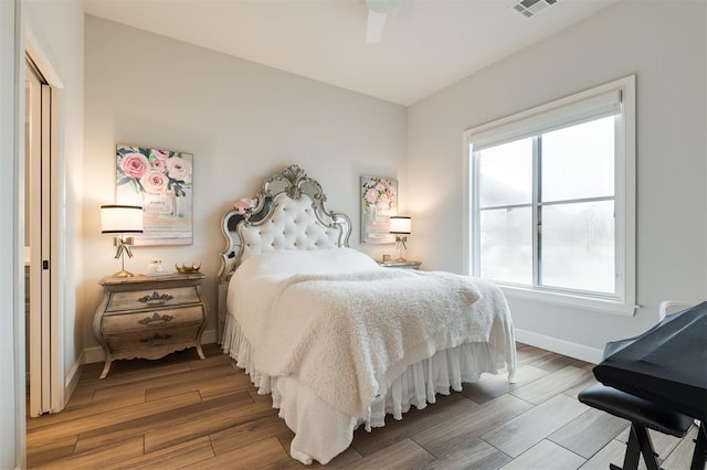 bedroom featuring visible vents, ceiling fan, baseboards, and wood finished floors