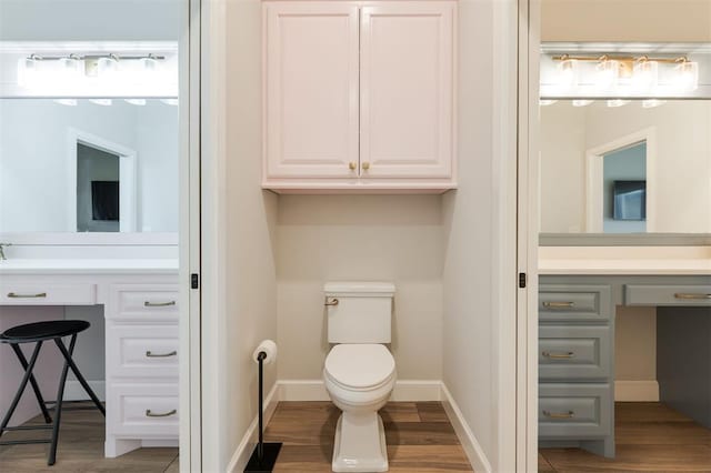 bathroom with toilet, baseboards, wood finished floors, and vanity