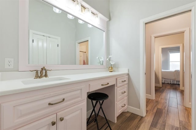 ensuite bathroom with ensuite bath, wood finished floors, vanity, and baseboards