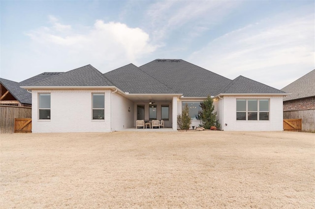 back of house with a shingled roof, a patio area, a fenced backyard, and brick siding