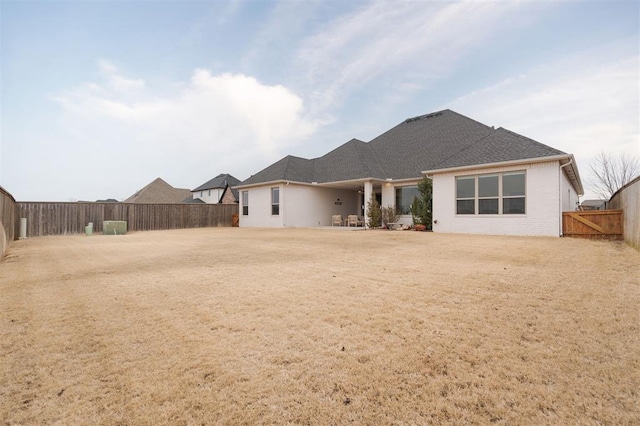 rear view of house with roof with shingles and a fenced backyard