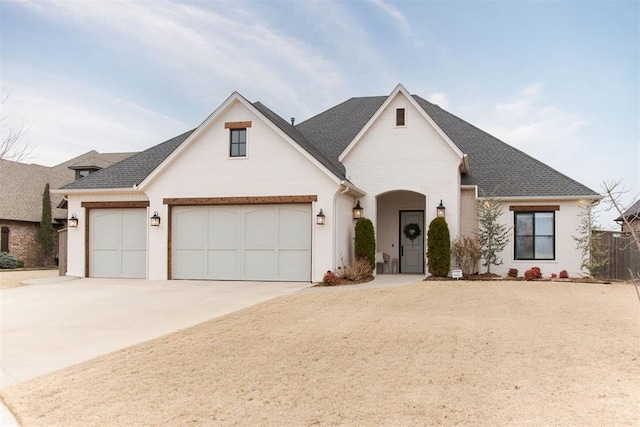 view of front of home featuring driveway, roof with shingles, an attached garage, fence, and brick siding