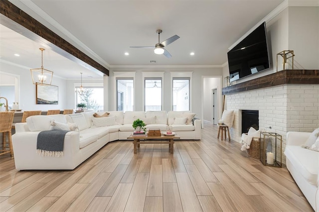 living area featuring recessed lighting, ceiling fan with notable chandelier, a fireplace, ornamental molding, and wood tiled floor